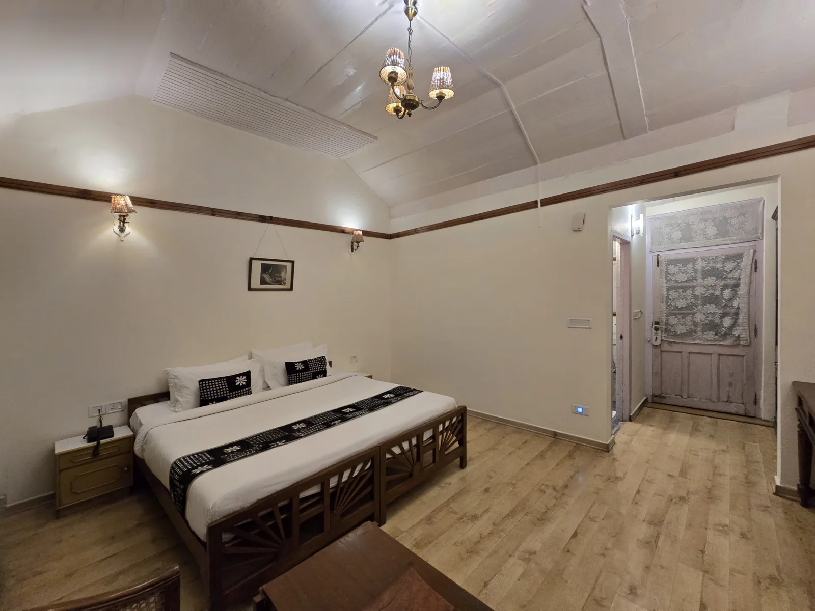 Heritage Classic room looking towards the door, with a chandelier and wall lamps above the bed