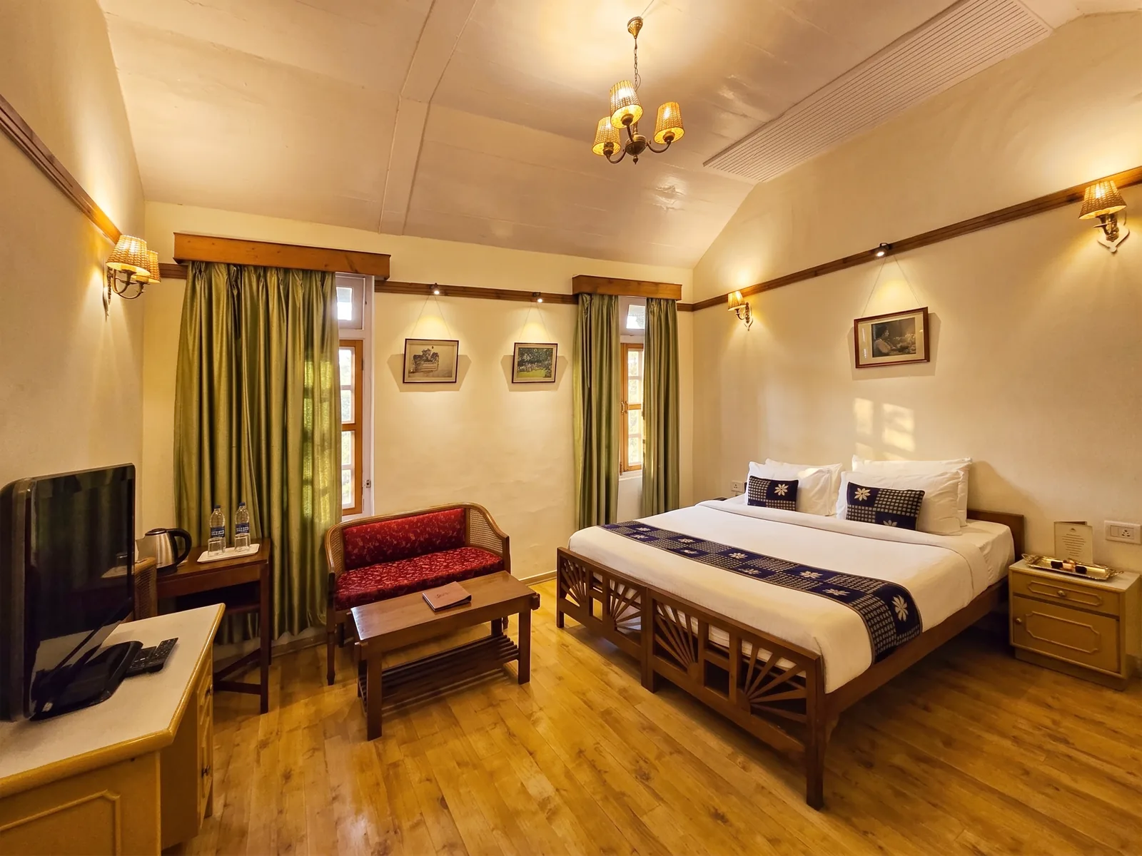 Heritage Classic room — vaulted ceiling, chandelier, green silk curtains and a carved king bed at Woodville Palace