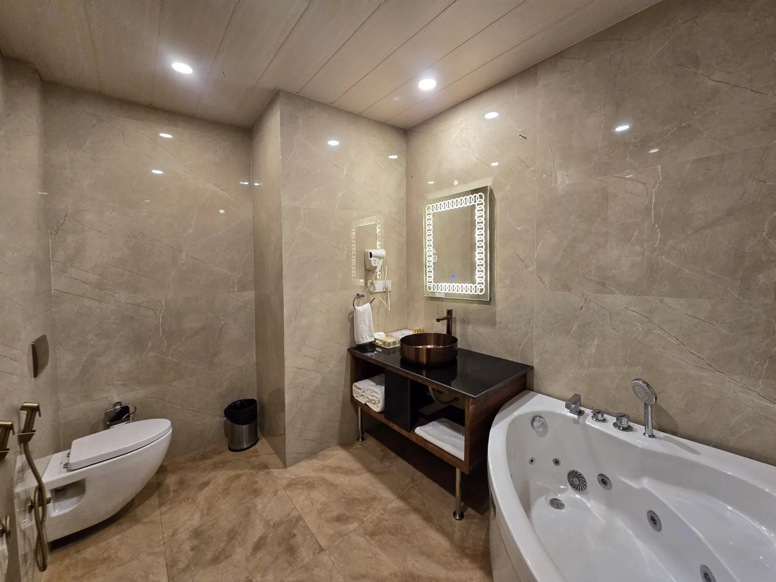 Himalayan Suite bathroom with a corner jacuzzi, copper basin and backlit mirror