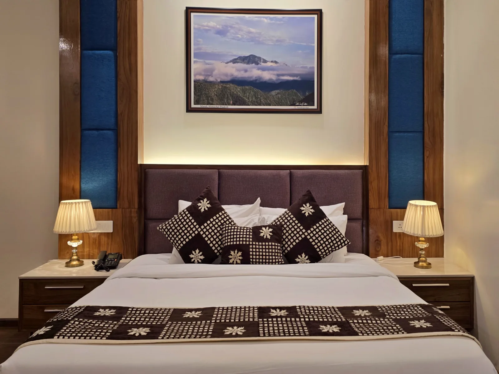 Imperial Room headboard with a framed mountain print and twin bedside lamps