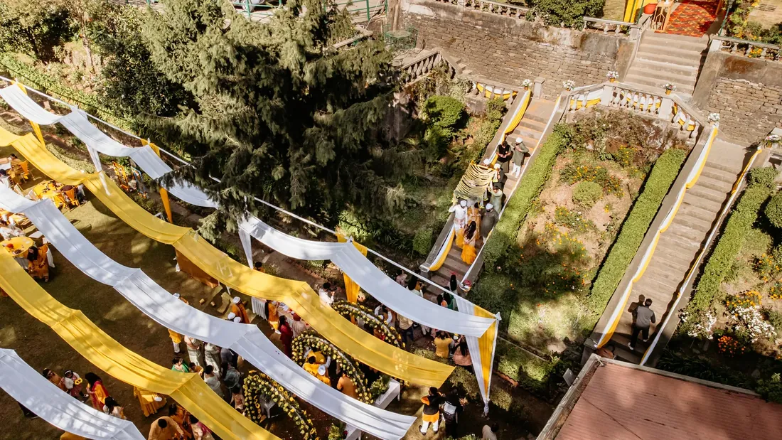 Aerial view of Woodville Palace Shimla during a haldi ceremony — marigold-yellow drapes across the lawn